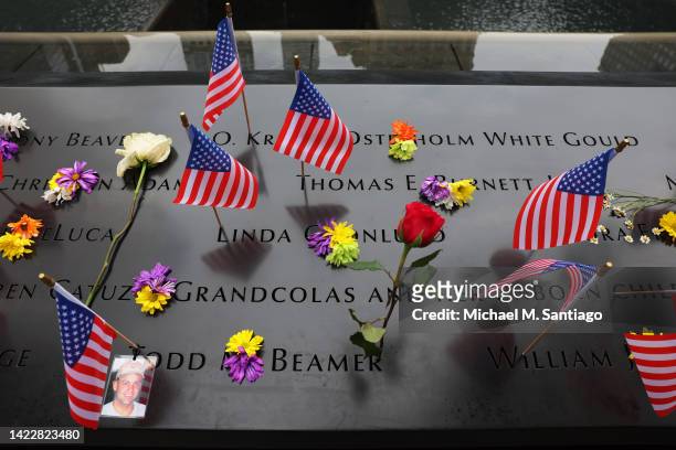 Flowers and American flags are seen on the names of victims of the 9/11 terror attack on the North Tower Memorial Pool during the annual 9/11...
