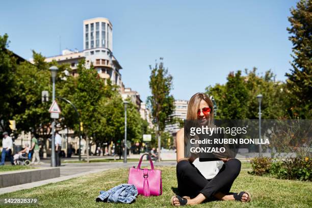 mid adult caucasian woman siting on urban meadow using digital tablet in street in zaragoza, spain. relax concept. - zaragoza city stock pictures, royalty-free photos & images