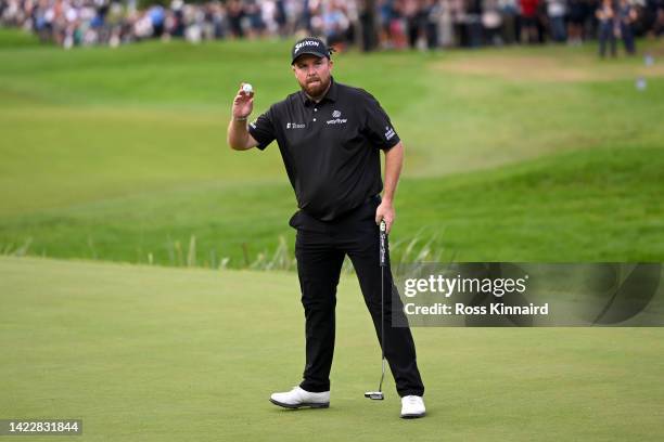 Shane Lowry of Ireland raises their ball and gestures to the crowd after putting on the 18th hole during Round Three on Day Four of the BMW PGA...