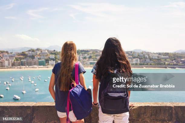 teenage girls with backpack looking at the sea - destination de voyage 個照片及圖片檔