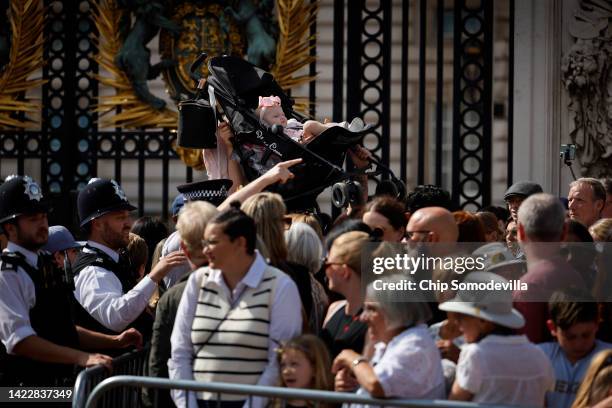 As the crush of people becomes too much, a baby in a stroller is lifted out of the crowd outside the gates of Buckingham Palace as people wait to...