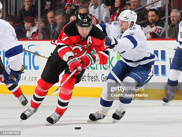 Ilya Kovalchuk of the New Jersey Devils plays the puck while being defended by Brett Clark of the Tampa Bay Lightning during the game at the...