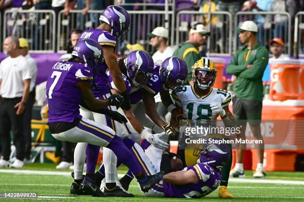 Harrison Smith of the Minnesota Vikings is helped up off the field by teammates while Randall Cobb of the Green Bay Packers looks on during the...