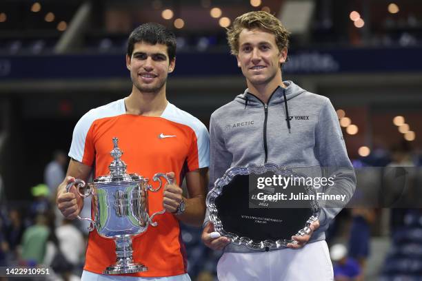 Casper Ruud of Norway holds the runner-up trophy alongside Carlos Alcaraz of Spain who celebrates with the championship trophy after winning their...