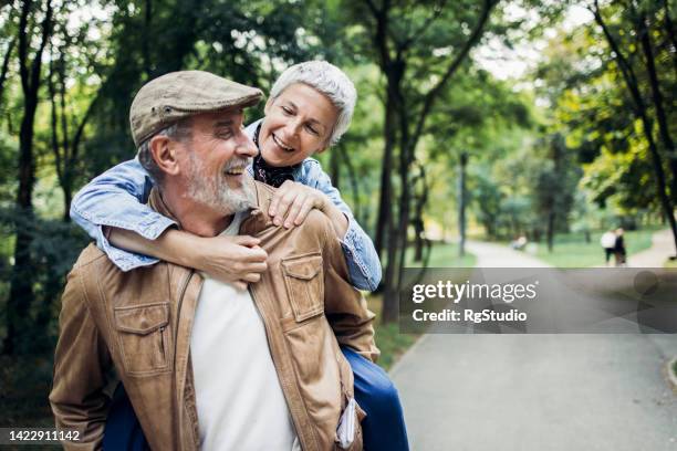 feliz idoso carregando sua esposa e se divertindo no parque - 60 64 anos - fotografias e filmes do acervo