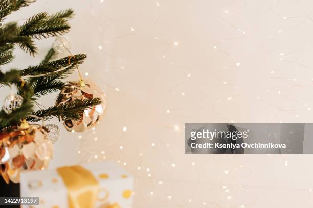 photo of luxury gift boxes under christmas tree, new year home decorations, golden wrapping of santa presents, festive tree decorated with garland, baubles, traditional celebration. copy space - grenzbaum stock-fotos und bilder
