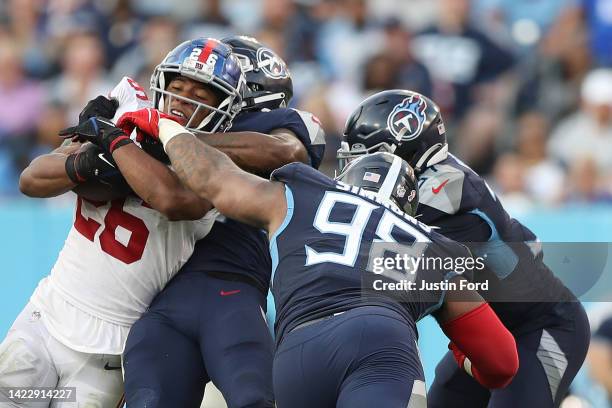Defensive tackle Jeffery Simmons of the Tennessee Titans and other defenders tackle running back Saquon Barkley of the New York Giants during the...