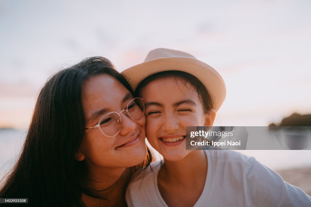 Sisters having a good time on beach at sunset, Japan