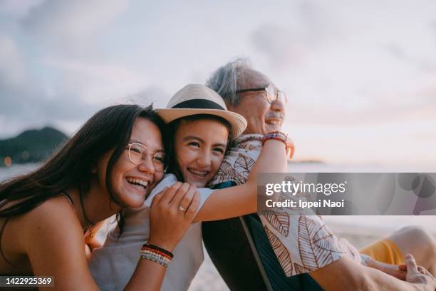 grandfather and granddaughters having fun on beach - familia multigeneracional fotografías e imágenes de stock