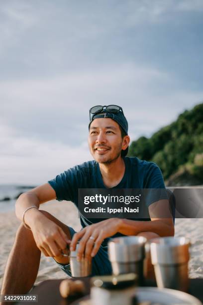 man having a good time at beach campsite - camping chair stock pictures, royalty-free photos & images