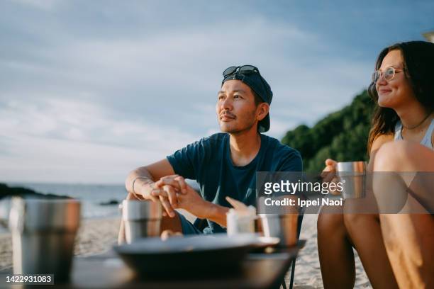 man having a good time at beach campsite - アウトドア　日本人 ストックフォトと画像
