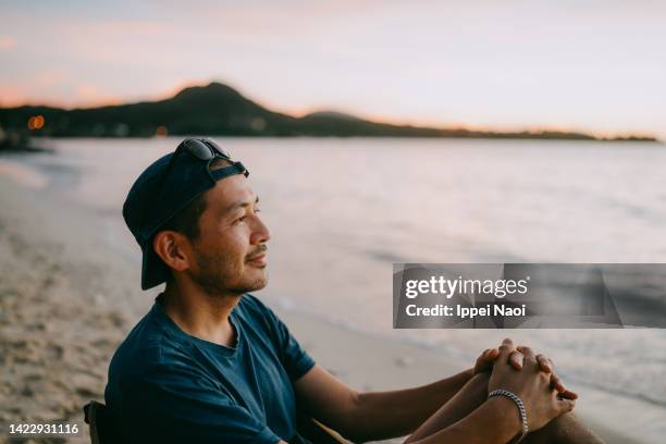 man pondering on beach at sunset - sitting profile view stock pictures, royalty-free photos & images