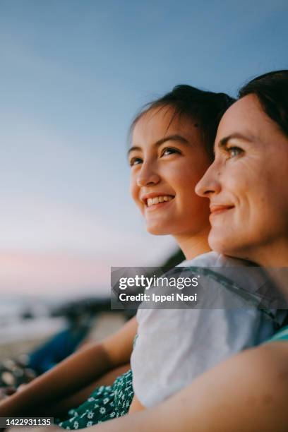 mother and daughter enjoying sunset on beach - east asia stock pictures, royalty-free photos & images