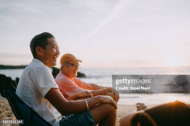 man having a good time with his senior father on beach at sunset - okinawa prefecture fotografías e imágenes de stock