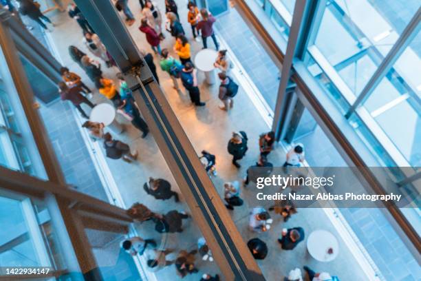 top view of people standing in hallway having coffee and sharing ideas. - interactief stockfoto's en -beelden