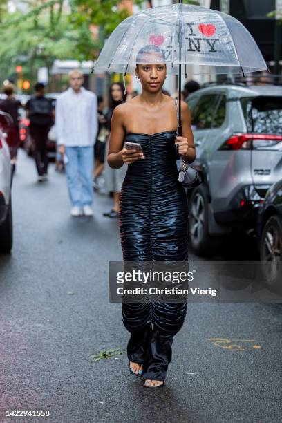 Guest wearing black off shoulder dress with I love NY umbrella outside Puppets & Puppets on September 11, 2022 in New York City.