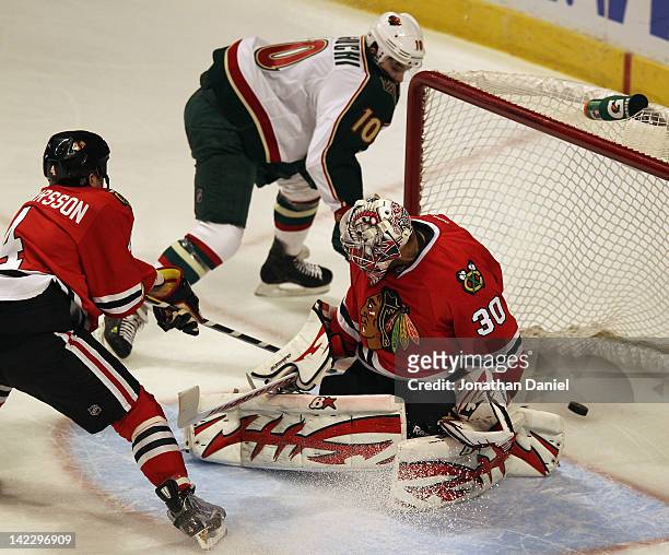 Devin Setoguchi of the Minnesota Wild scores a goal against Ray Emery of the Chicago Blackhawks as Niklas Hjalmarsson tries to defend at the United...