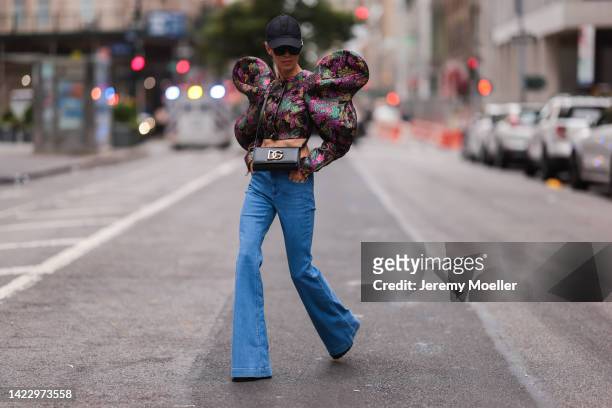 Denisa Palsha wearing a black cap, black Burberry shades, a colorful Dolce Gabanna jacket, a black Dolce Gabanna leather bag, blue Stella McCartney...