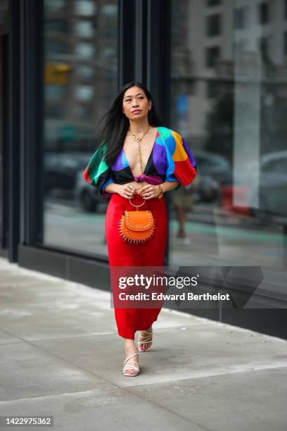 Miki Cheung wears gold and diamonds earrings, a gold large logo chain long pendant necklace from Fendi, a multicolored print pattern V-neck / puffy...