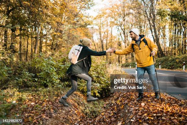 hiker helping his girlfriend to jump over a ditch - ditch stock pictures, royalty-free photos & images