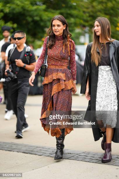 Katie Holmes wears a burgundy and brown print pattern turtleneck / long sleeves / ruffled long dress, a black shiny leather shoulder bag, silver...