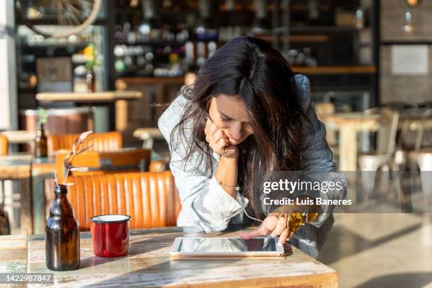 woman using a digital tablet while leaning on the table in a coffee shop. - coffee table reading mug stock pictures, royalty-free photos & images