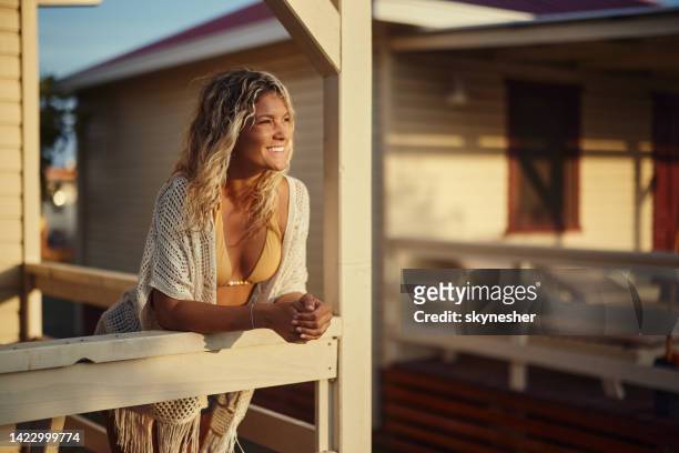 happy woman enjoying on a patio of a beach house. - beach house balcony stock pictures, royalty-free photos & images