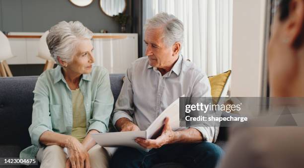 senior and retired couple talking with finance documents in meeting with lawyer, planning retirement and will paperwork together in home. mature man and woman in discussion about pension with advisor - erfenis stockfoto's en -beelden
