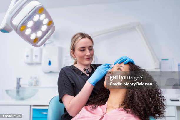 cosmetic nurse injecting botox into patient in dental surgery - botox injections stock pictures, royalty-free photos & images
