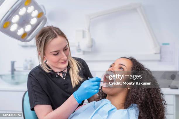 female dentist checking teeth of patient with retractor - dentist stock pictures, royalty-free photos & images