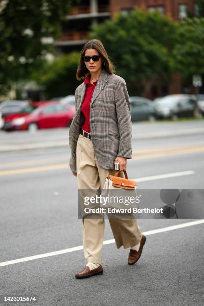 Guest wears black sunglasses, a red polo shirt, a gray and black checkered print pattern blazer jacket, a black shiny leather belt, beige large...