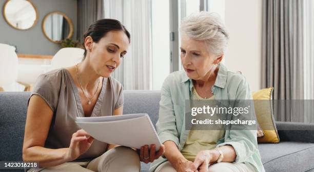 caregiver talking to senior woman about insurance, support with finance documents and help reading retirement paperwork on the sofa in home. girl helping elderly person with alzheimer care at house - rate of love stock pictures, royalty-free photos & images