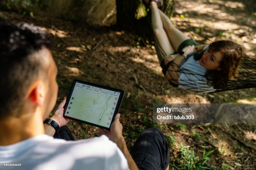 Millennial-aged travelers looking at a map on a digital tablet while enjoying nature