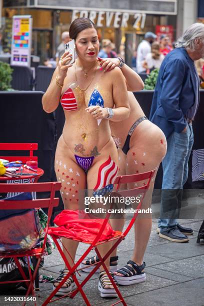 zwei showgirls helfen sich gegenseitig bei der körperbemalung - times square body paint stock-fotos und bilder