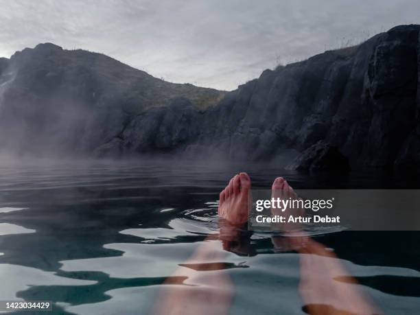 man relaxing floating on water with feet in a hot spring in iceland. - hot men feet photos et images de collection