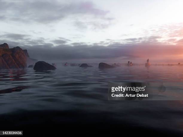 people contemplating the sunset from thermal pool with infinity view in iceland. - reykjavik stock pictures, royalty-free photos & images
