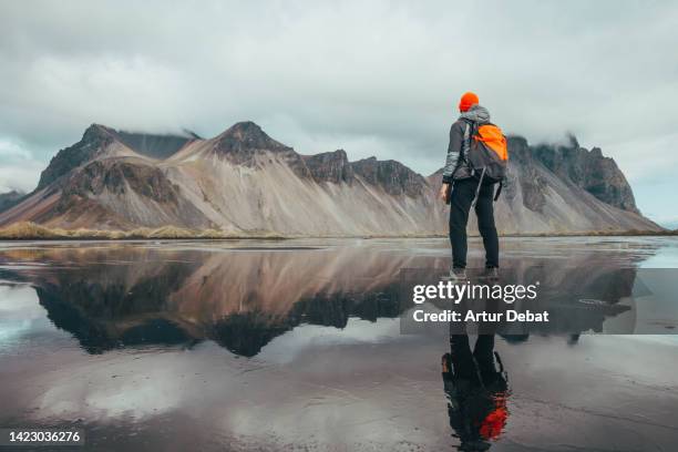 backpacker with the vestrahorn mountains seen from the wetlands of stokksnes in iceland. - backpacker road stockfoto's en -beelden