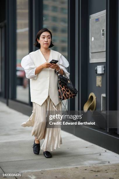 Guest wears silver earrings, a gold chain necklace from Van Cleef and Arpels, a white V-neck / puffy long sleeves / oversized blazer jacket, a gold...