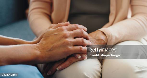 hand holding friends or family for empathy, love and support in difficult grief at home or house. hands of unity, care and solidarity man and woman or sorry people forgive and trust in family home - mourner stockfoto's en -beelden