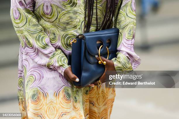 Guest wears a green / purple and camel print pattern long shirt, matching green / purple and camel print pattern large pants, a navy blue shiny...