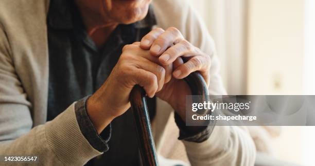senior, hands and walking stick for disability man with depression, anxiety and sad mental health or stress. closeup of mobility aid, cane or support for elderly pensioner in nursing home living room - walking stick stock pictures, royalty-free photos & images