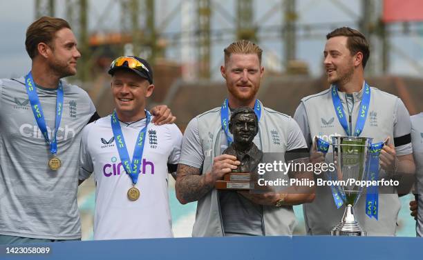 Ben Stokes of England holds the trophy with Stuart Broad , Ollie Pope and Ollie Robinson after England won the third Test and the series against...