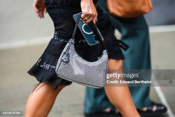 Guest wears a black embroidered sequined / ripped knees skirt, a black shiny leather with embroidered rhinestones Reedition 2000 handbag from Prada,...
