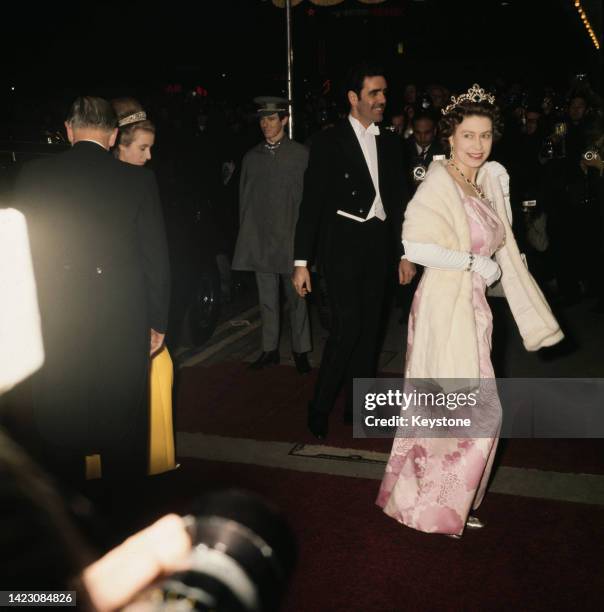 Queen Elizabeth II , wearing a pink floral design evening gown with a white fur evening wrap, attends an reception at the Grosvenor House Hotel on...