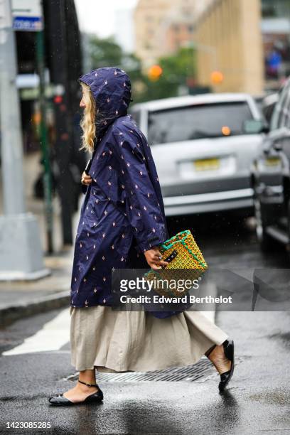 Guest wears a navy blue with embroidered white hand print pattern hoodie oversized long coat, a beige long dress, a yellow and green braided handbag,...