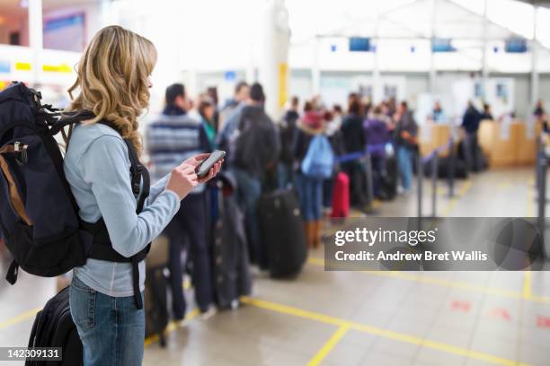 female traveller texting at airport check-in desk - esperar na fila imagens e fotografias de stock