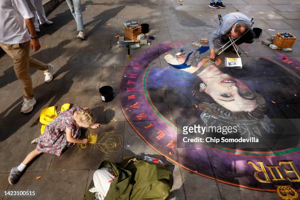 Three-year-old Violet Williams works on her own drawing next to artist Julian Beever as he works on a chalk portrait of Queen Elizabeth II on the...