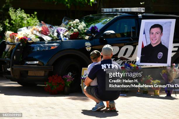 Boulder police officer Ryan McAuley and his son Hank sit beside the police cruiser belonging to fallen Arvada police officer Dillon Michael Vakoff...