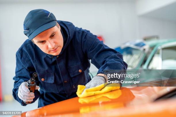 professional worker polishing with input the shining chemical and wiping a car with a rag while polishing in auto car repair color garage. - auto detailing stock pictures, royalty-free photos & images