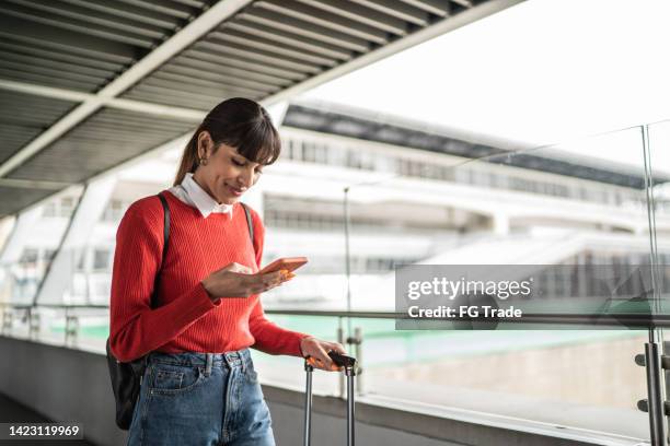 reisende junge frau mit handy in einer u-bahn-station - airport phone stock-fotos und bilder